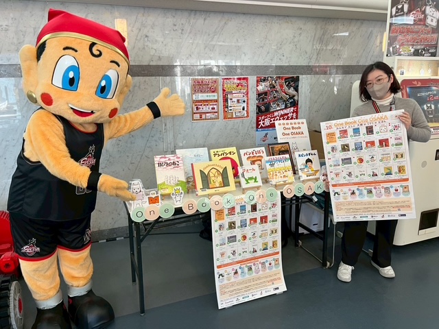 まいどくんと職員が出張投票コーナーを挟んで立っている写真