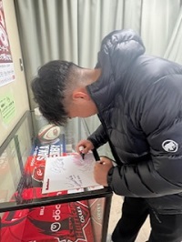 色紙にサインをするレッドハリケーンズの選手