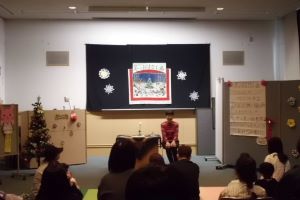 女性がろうそくの灯りの横でお話を語っている写真