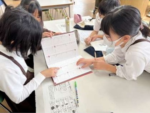 子どもたちが図鑑を使って調べる様子